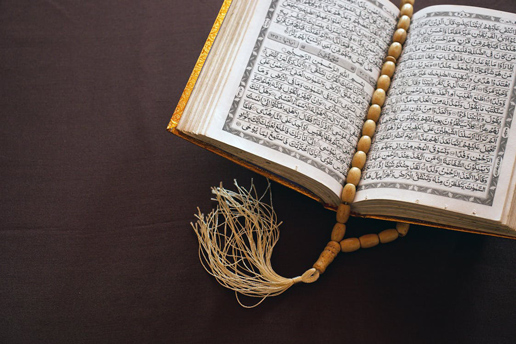 Open Quran with prayer beads symbolizing Eid al-Fitr spirituality and holiday travel with Ethiopian Airlines.
