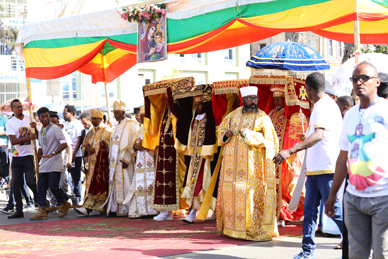 Priests carrying tabots during the Timket procession, surrounded by traditional canopies and celebrating crowds.