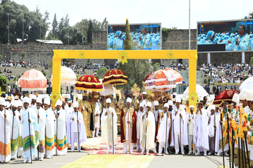 Priests in white and gold under colorful umbrellas during the Meskel Festival celebration in Ethiopia.