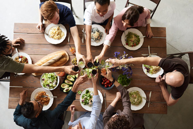 Group raising glasses in a cheerful Thanksgiving toast, celebrating friendship, food, and holiday joy.