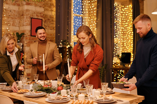 People arranging dishes on a warmly lit Thanksgiving table, capturing the joyful spirit of holiday meal prep.