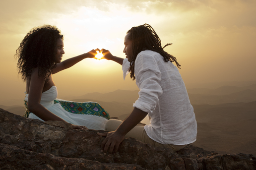 Couple forming a heart shape at sunset on a hilltop, capturing a warm and romantic Valentine’s Day moment.