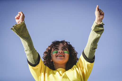 Excited football fan cheering with raised arms while celebrating a World Cup match victory outdoors.