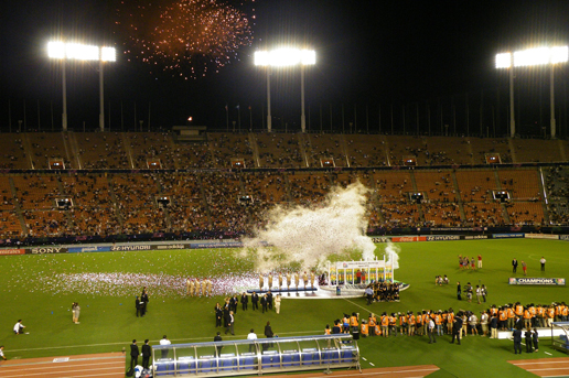 Football stadium celebration with fireworks, confetti, and a championship ceremony during a major international match.