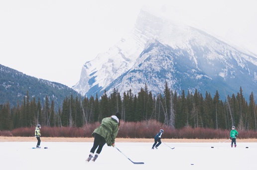 Travelers playing ice hockey on a frozen Canadian lake, showcasing winter thrills for Ethiopian Airlines visitors.