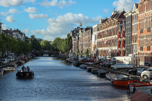 Amsterdam canal lined with autumn colors and boats under a bright blue sky
